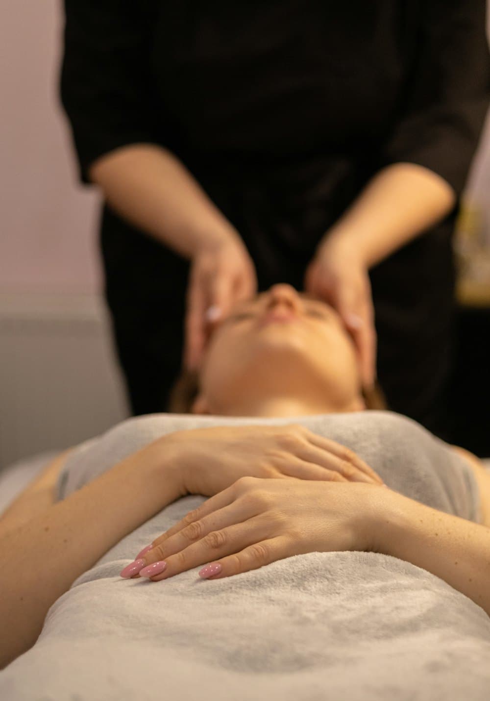 Kỹ thuật viên massage mặt cho khách nằm trên giường