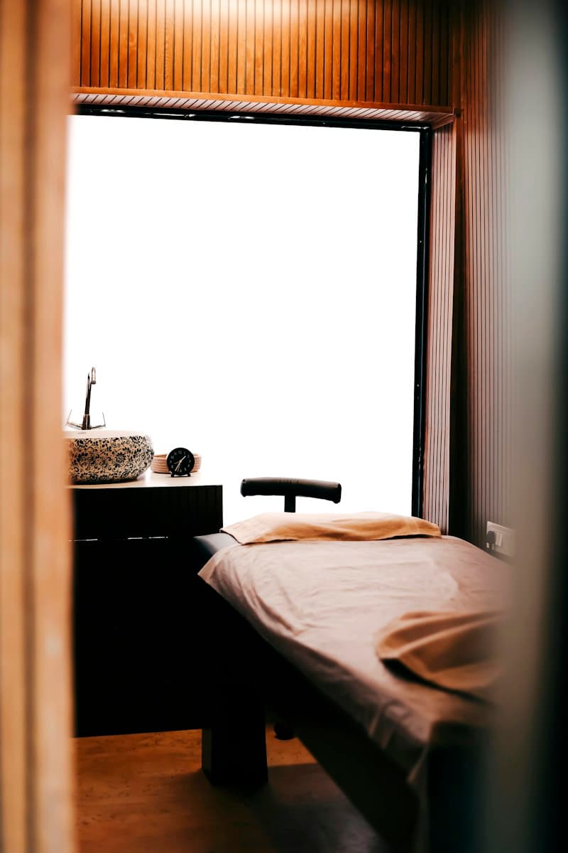 Phòng trị liệu nhỏ với giường massage cạnh cửa sổ